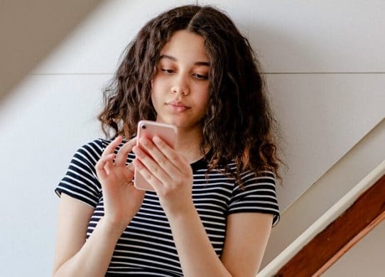 Teenage girl texting in room