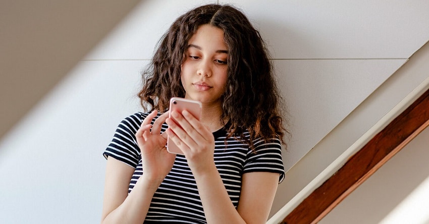 Teenage girl texting in room